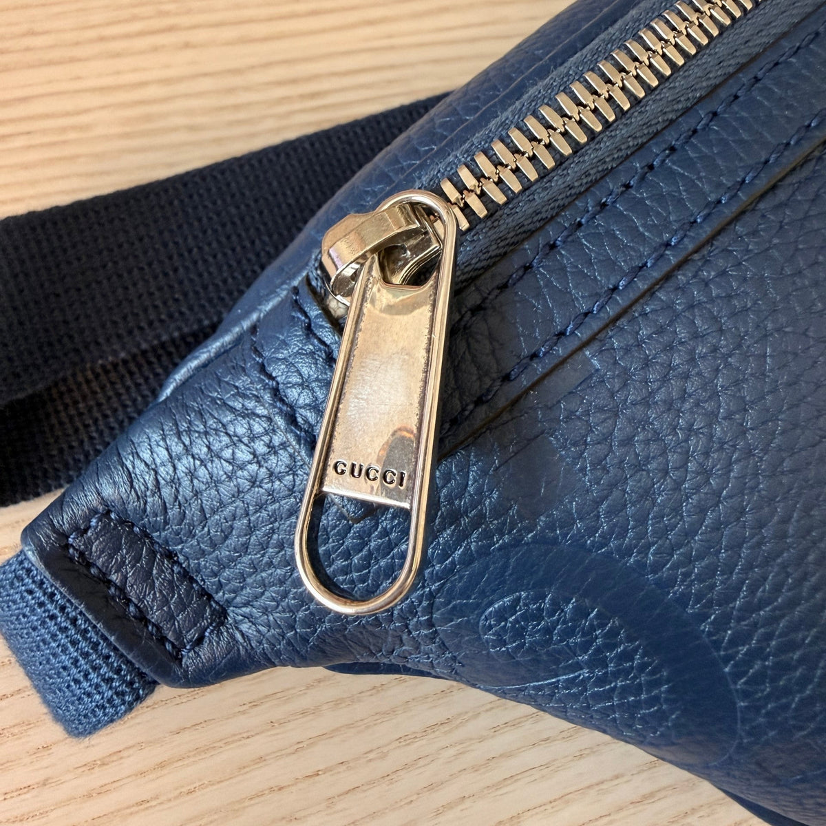 Luxe Vault Gucci blue embossed leather belt bag featuring a silver metal zipper pull with engraved logo detail