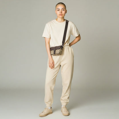 Model wearing a Luxe Vault Gucci monogram mini crossbody bag with a brown strap over a beige lounge set
