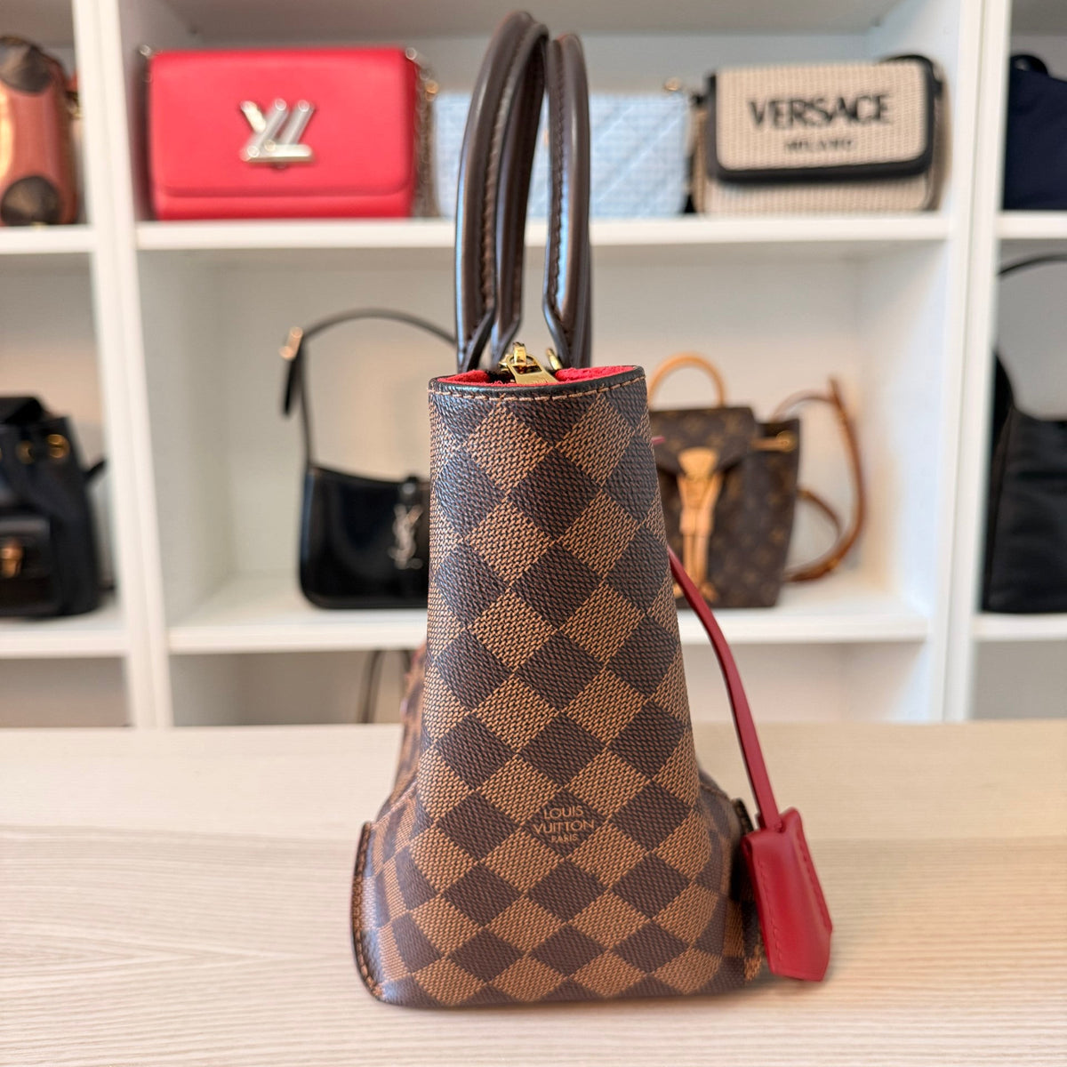 Luxe Vault Louis Vuitton Caissa PM handbag in Damier Ebene canvas with red leather accents, side profile view